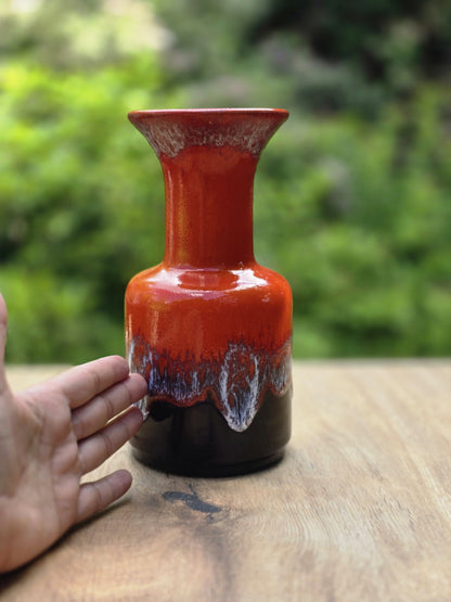 Rote Vintage Keramikvase von Jasba mit schwarzem Sockel und Größenvergleich neben einer Hand