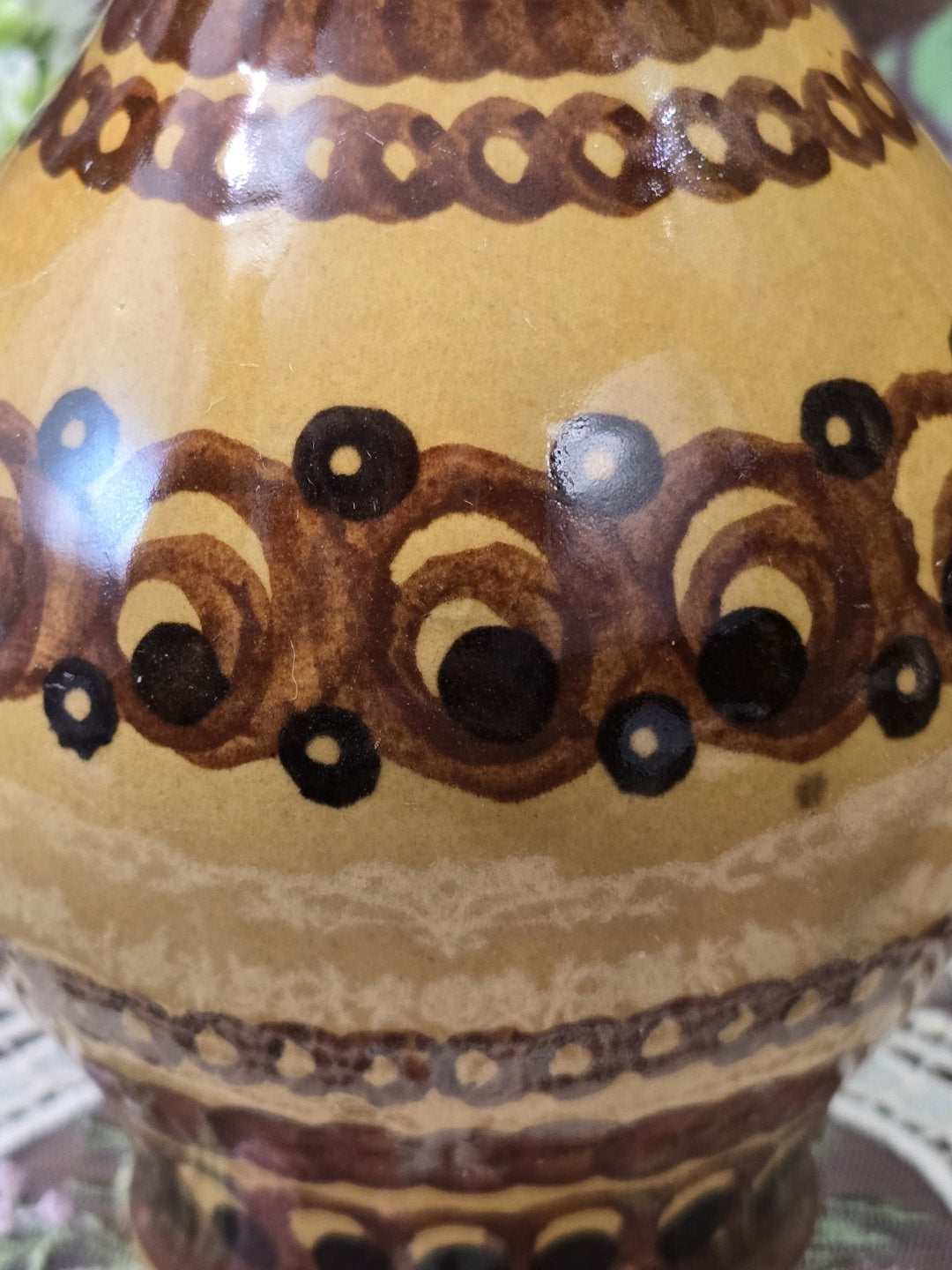 Vintage Keramikkrug mit braun glasierter Mündung und hell ockerfarbener Innenfläche in schräger Detailansicht von oben.