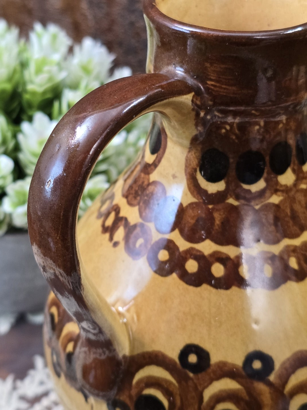 Vintage Keramik-Henkelkrug mit handgemaltem Kreis- und Bogenmuster in Braun und Schwarz in naher Detailaufnahme des Korpus.