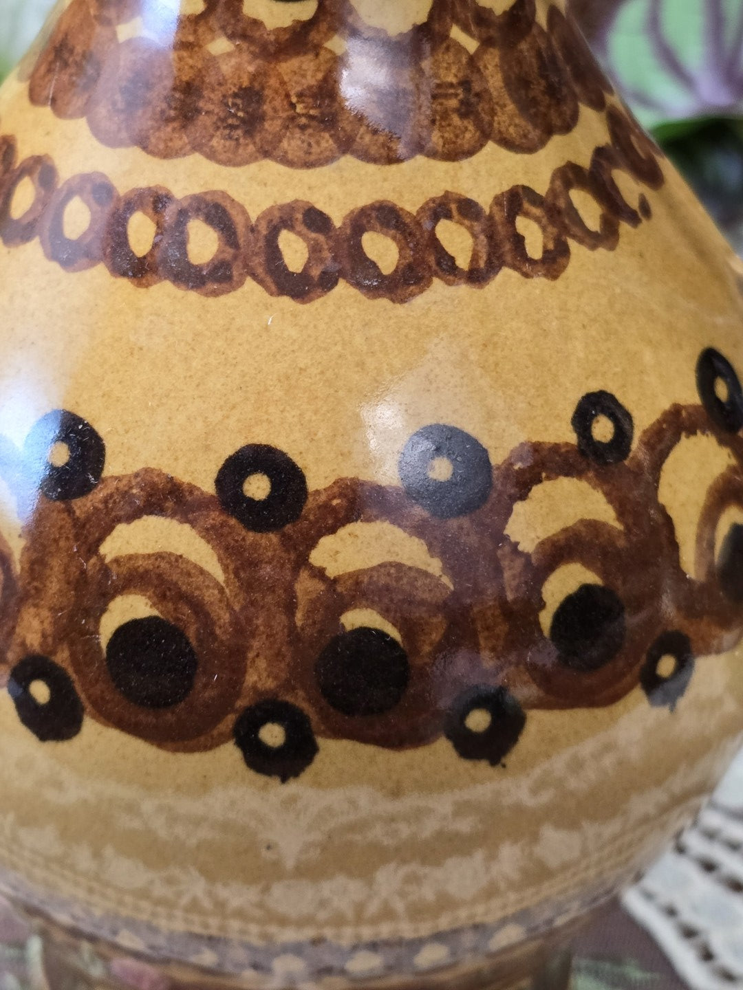 Vintage Keramikkrug mit umlaufendem braun-schwarzem Dekor und hellem Musterband am unteren Korpus in Nahaufnahme.