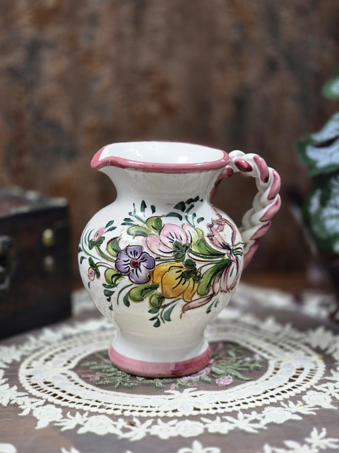 Keramik Kännchen mit Blumendekor, rosa Rand, bauchiger Form, Tülle und geflochtenem Henkel auf Spitzendecke