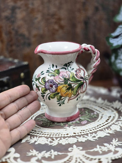 Keramik Kännchen mit handbemalten Blumen, rosa Akzenten und geflochtenem Henkel neben einer Hand als Größenvergleich