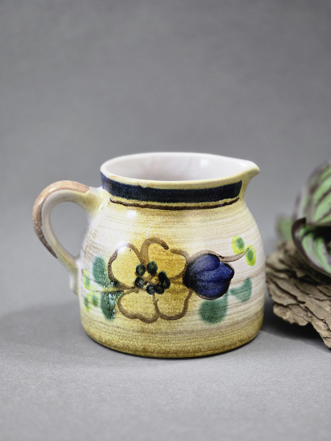 Bauchiges Keramik-Milchkännchen mit Ausguss, gelbem Blumenmotiv, blauer Knospe und grünem Blattdekor