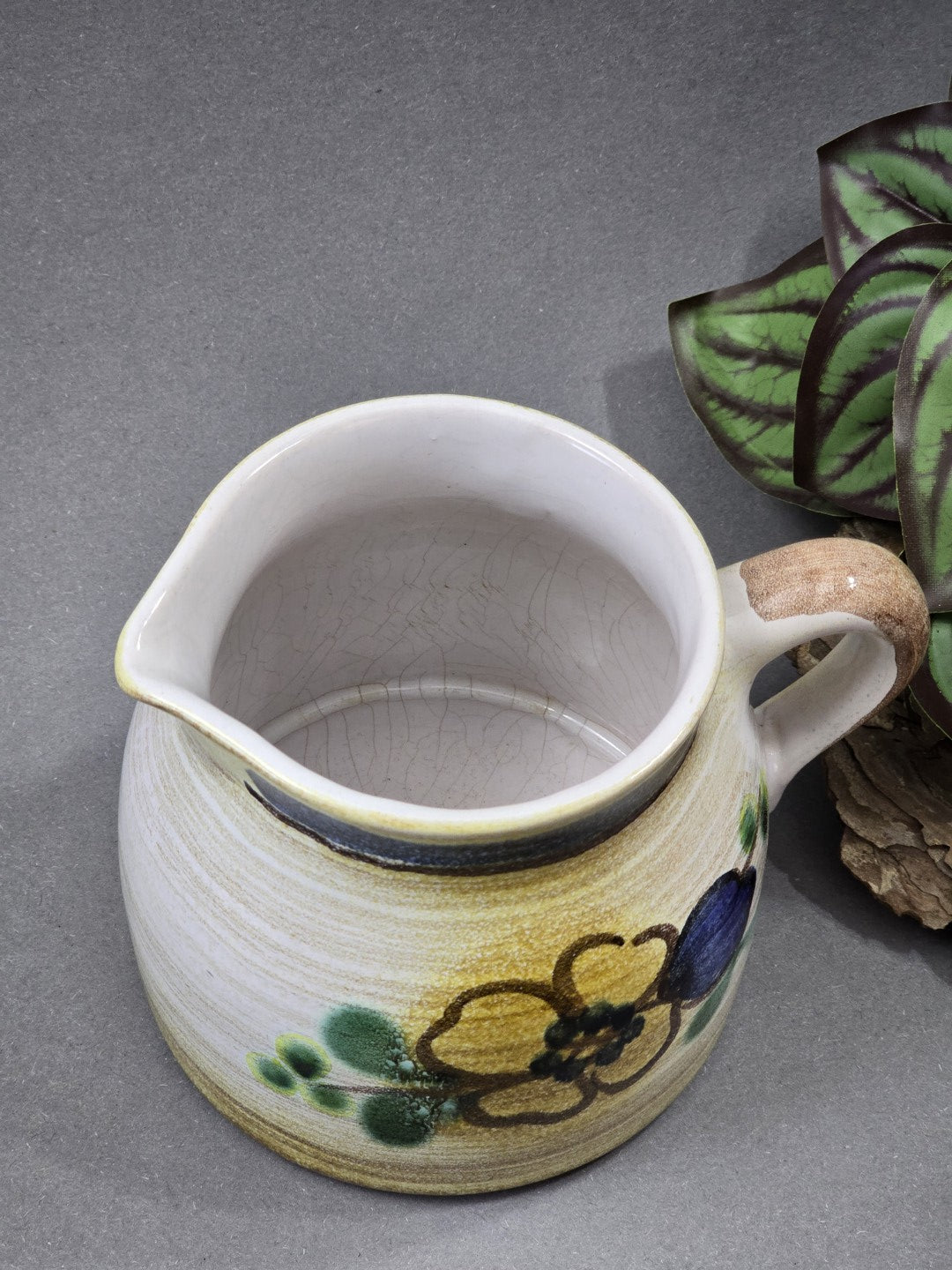Draufsicht auf ein kleines Keramik-Milchkännchen mit weißem Innenraum, Ausguss, Craquelé und floralem Außendekor