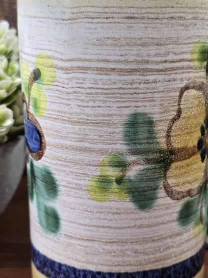 Detailaufnahme des floralen Dekors der Vintage Keramikvase mit gelber Blüte, blauem Blütenmotiv und grünen Blättern.