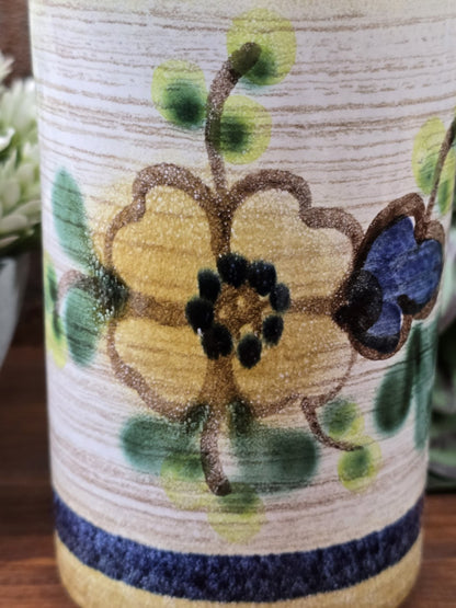 Nahaufnahme der Vintage Keramikvase mit blauem Blütenmotiv, grünen Blättern und horizontaler Struktur im beigefarbenen Dekor.