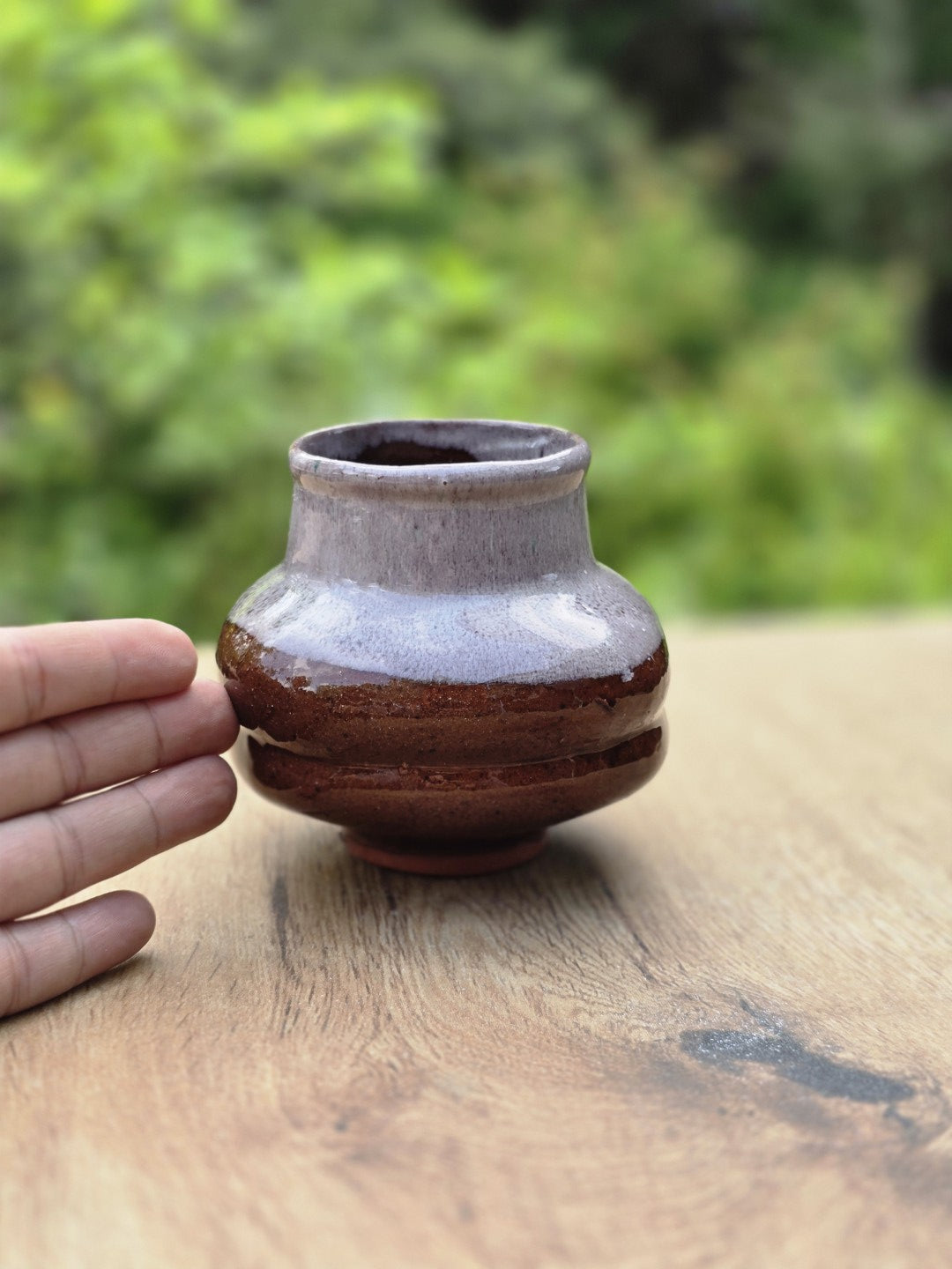 Vintage Keramikvase mit brauner und grauer Laufglasur neben einer Hand zur Einschätzung der Größe
