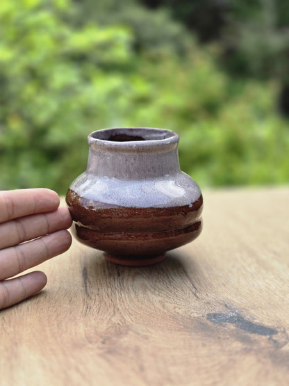 Vintage Keramikvase mit brauner und grauer Laufglasur neben einer Hand zur Einschätzung der Größe