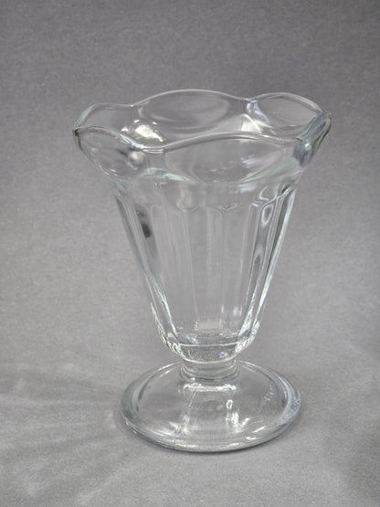 Einzelner klarer Glasbecher von vorne, mit tulpenförmiger Öffnung, senkrechten Rippen im Kelch und rundem Standfuß