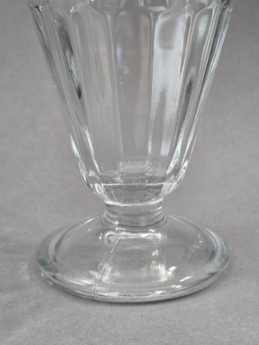 Detailbild vom unteren Bereich des Eisbechers mit rundem Fuß, kurzem Stiel und sichtbarer Pressnaht im klaren Glas
