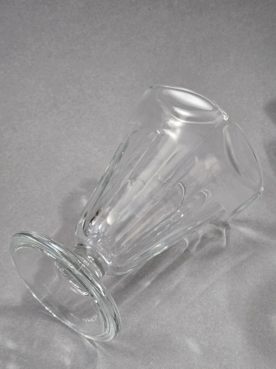 Der klare Eisbecher liegt seitlich, wodurch die Form von Fuß, Stiel, Kelch und gerippter Glasstruktur gut erkennbar ist