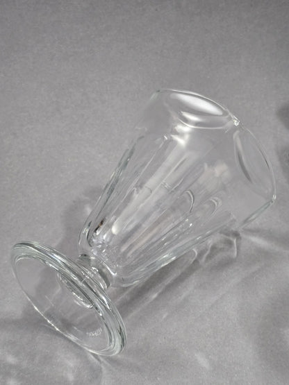 Der klare Eisbecher liegt seitlich, wodurch die Form von Fuß, Stiel, Kelch und gerippter Glasstruktur gut erkennbar ist