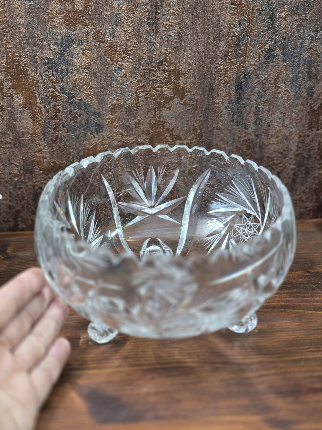 Blick von oben in eine geschliffene Kristallglasschale mit sternförmigen und blattartigen Schliffmotiven sowie gezacktem Rand.