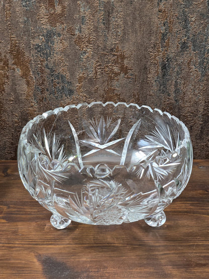 Vintage Kristallglasschale in Schrägansicht mit sichtbarem Innenraum, drei Füßen und dekorativem Stern- und Blattschliff.