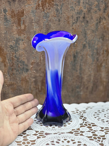 Glasvase mit blau-weißem Farbverlauf, geschwungenem Rand und klarem Fuß, neben einer Hand als Größenvergleich