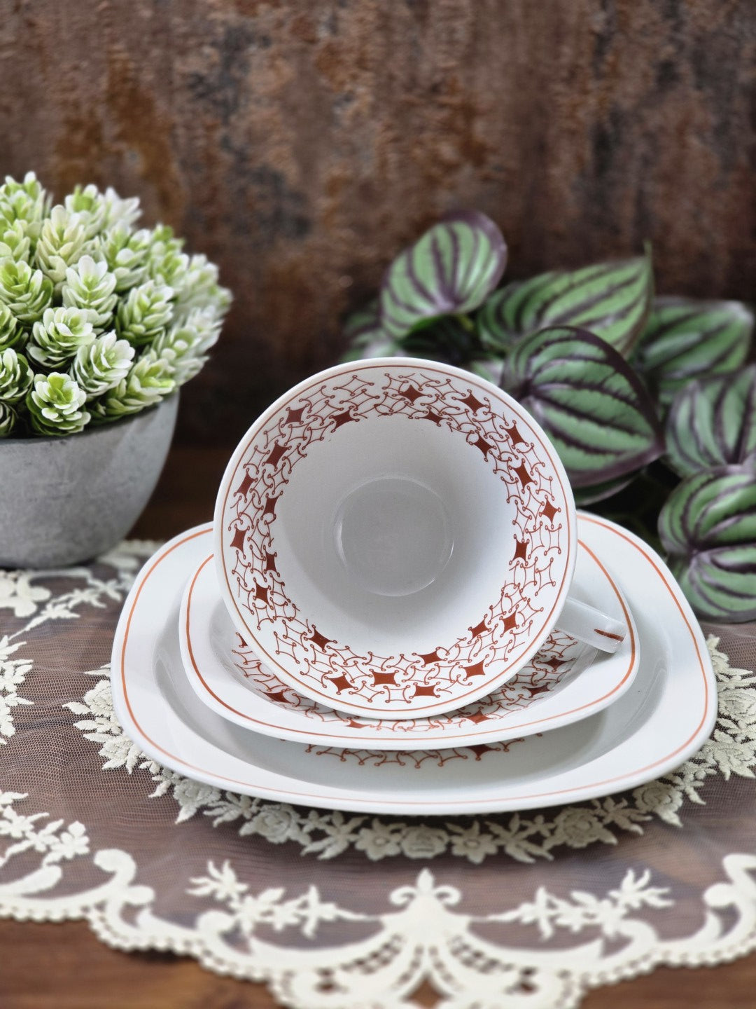 Vintage Porzellantasse mit Untertasse und Kuchenteller, braunrotem Dekor und rundem Innenmuster in Frontalansicht