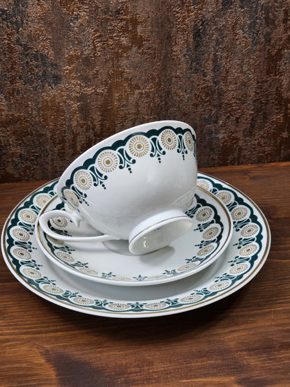 Vintage Lettin Porzellangedeck mit schräg liegender Tasse, grün-goldenem Dekor und Goldlinien auf Holztisch