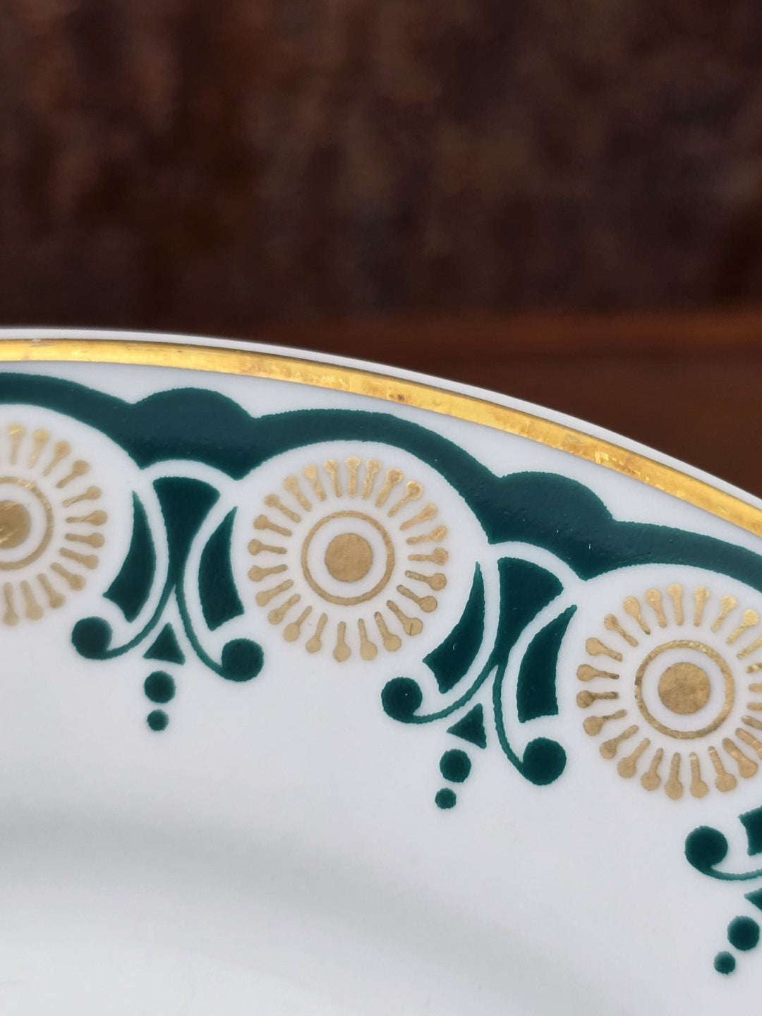 Vintage Porzellanteller mit Goldrand, grünem Ornamentdekor und goldenen Kreisformen in naher Detailansicht