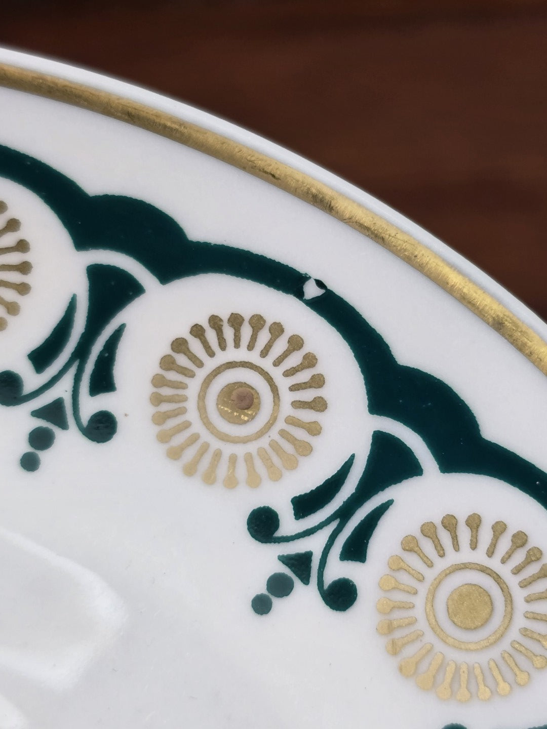 Vintage Porzellanteller mit grünem Ornamentband und goldenen Kreisdetails am Rand in extremer Nahaufnahme
