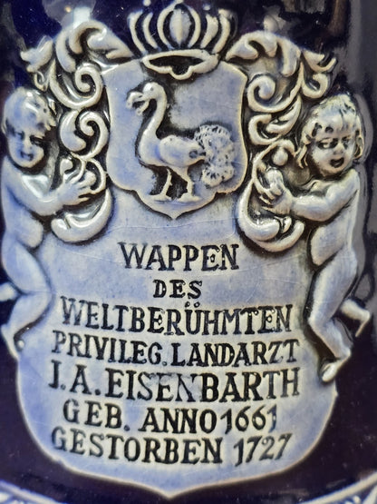 Vintage Bierkrug mit Eisenbarth-Wappen, zwei plastischen Figuren und beschriftetem Relief zu Johann Andreas Eisenbarth in Nahaufnahme.