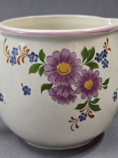 Detailaufnahme des floralen Dekors mit großen lila Blüten, gelber Mitte, kleinen blauen Blumen, grünen Blättern und rosa Randlinie.