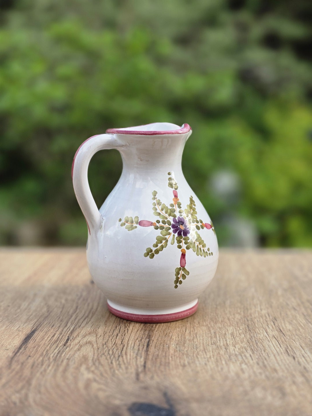 Kleiner Keramikkrug im Vintage-Stil mit heller Glasur, zartem rosa Rand, feinem Ausguss und handgemalten Blüten in Rosa, Lila und Grün.