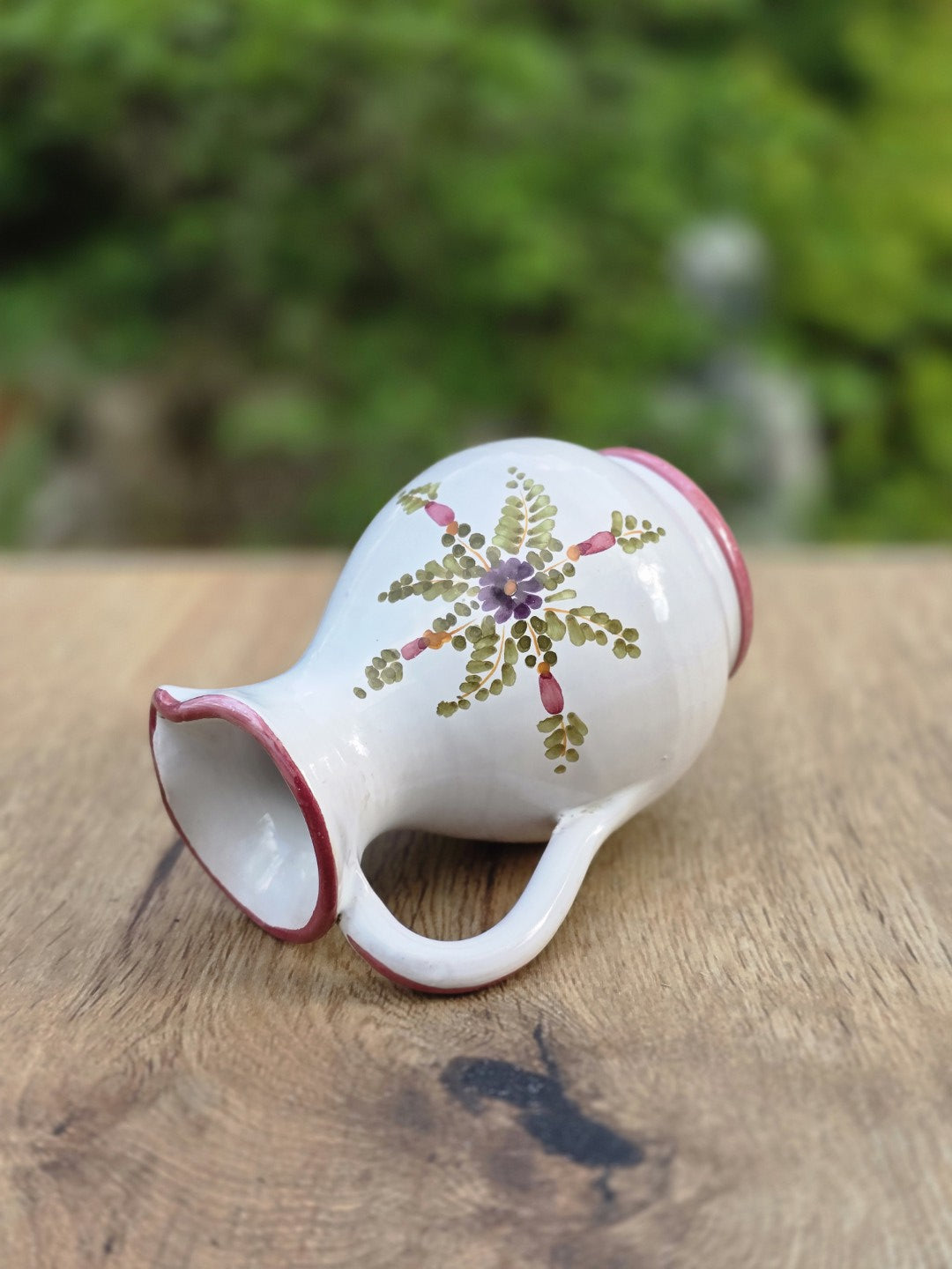 Bauchiger Vintage-Krug aus glasierter Keramik mit schmalem Hals, rosa Akzent am Rand und dekorativem Blumendekor in sanften Farbtönen.