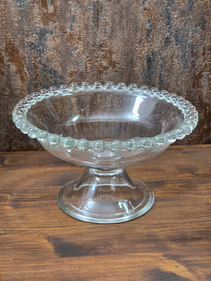 Vintage Pressglas Fußschale mit rundem Schalenkörper, Standfuß und Perlenrand aus klarem Glas in Frontalansicht