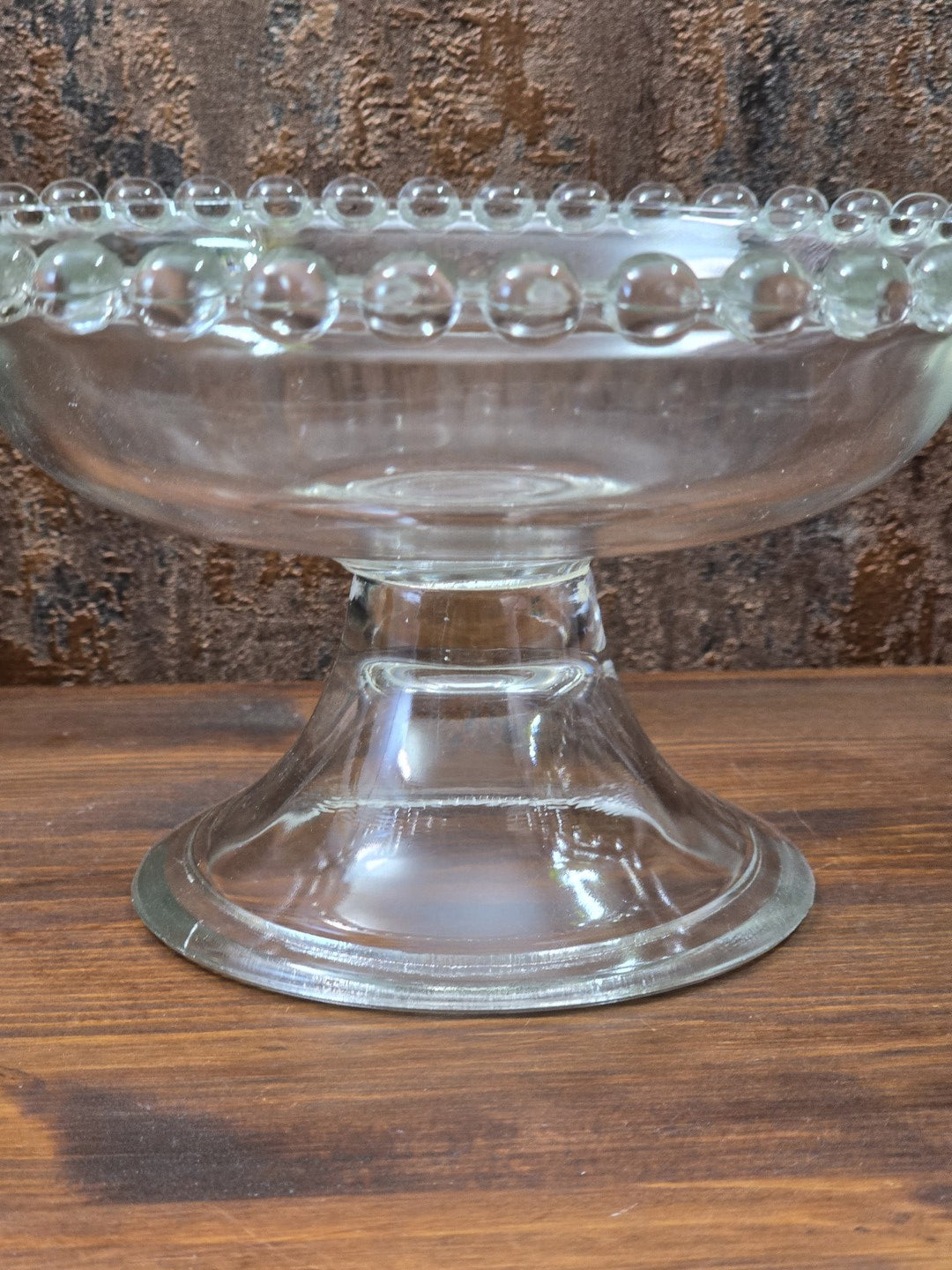 Vintage Pressglas Fußschale mit hohem Standfuß, klarem Glas und kugeligem Perlenrand in seitlicher Nahaufnahme