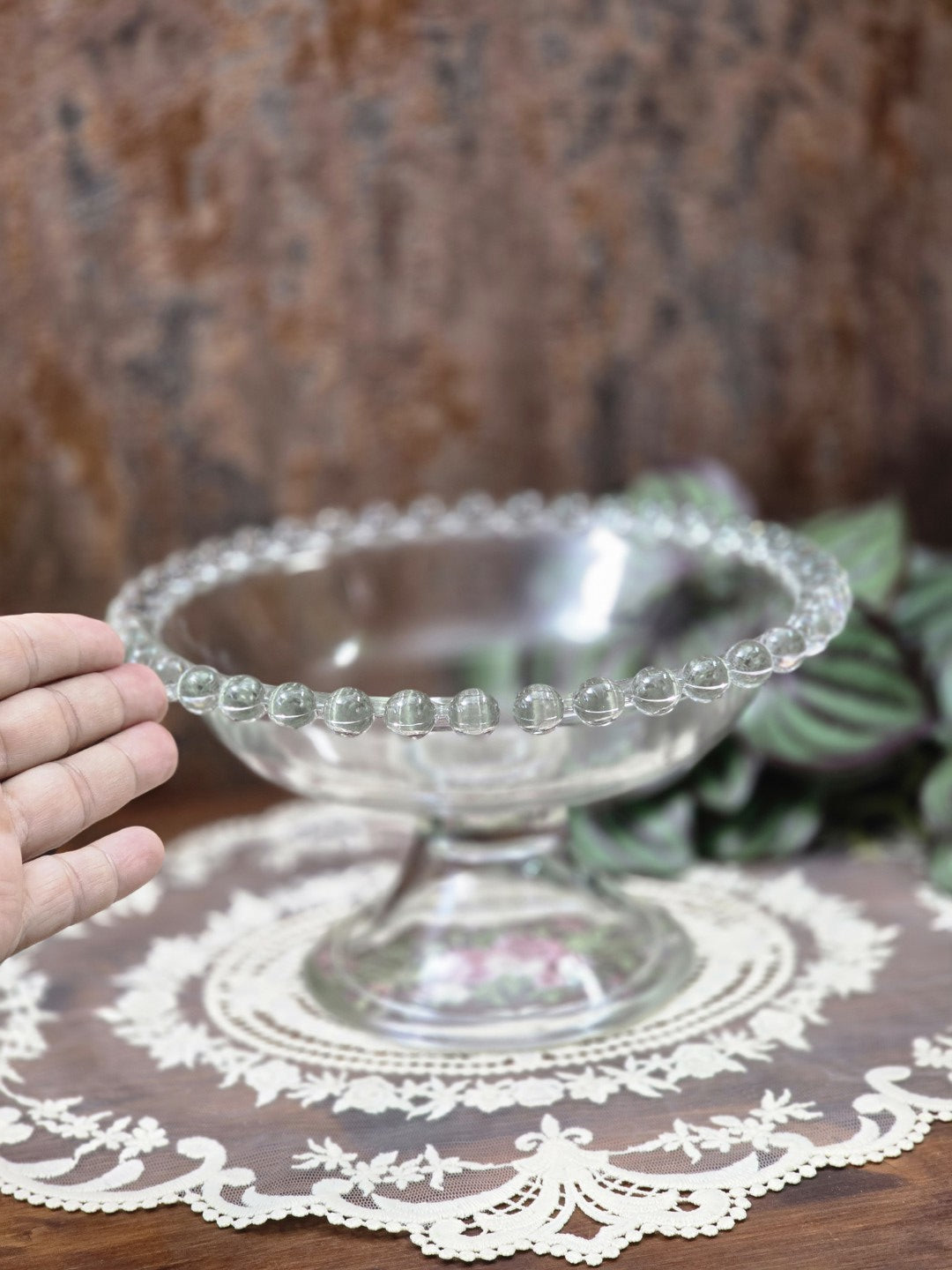 Vintage Pressglas Fußschale mit Perlenrand und Standfuß, von einer Hand als Größenvergleich seitlich gehalten