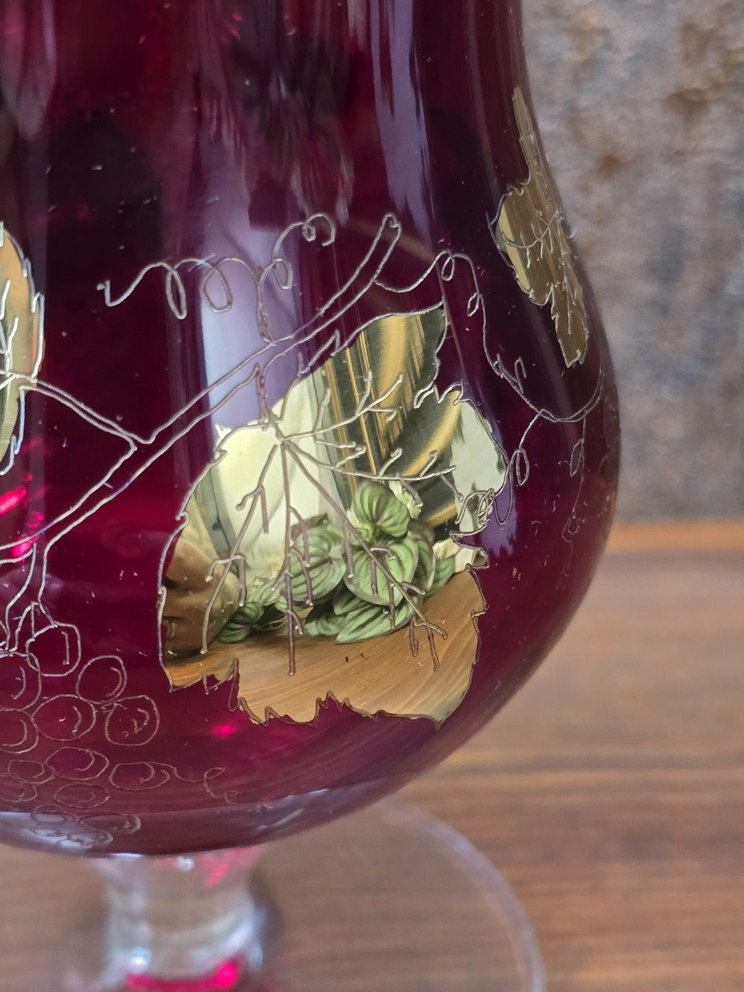 Rubinglas Pokal im Detail mit goldenem Weinblattdekor, feinen Rankenlinien und sichtbaren Spiegelungen