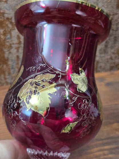Rubinglas Pokal im Detail mit Goldrand, dunkelrotem Glas und feinen Weinranken unter der Öffnung