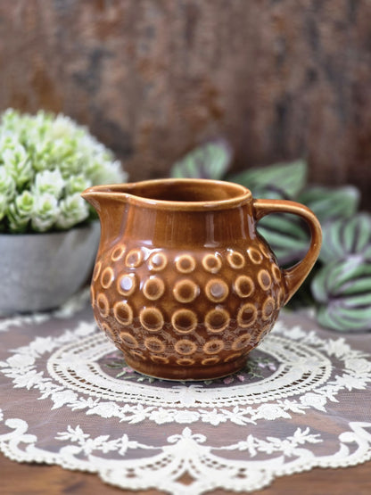 Vintage Rusalka Milchkännchen aus brauner Keramik mit bauchiger Form, Ausguss und umlaufendem Kreisdekor leicht seitlich fotografiert