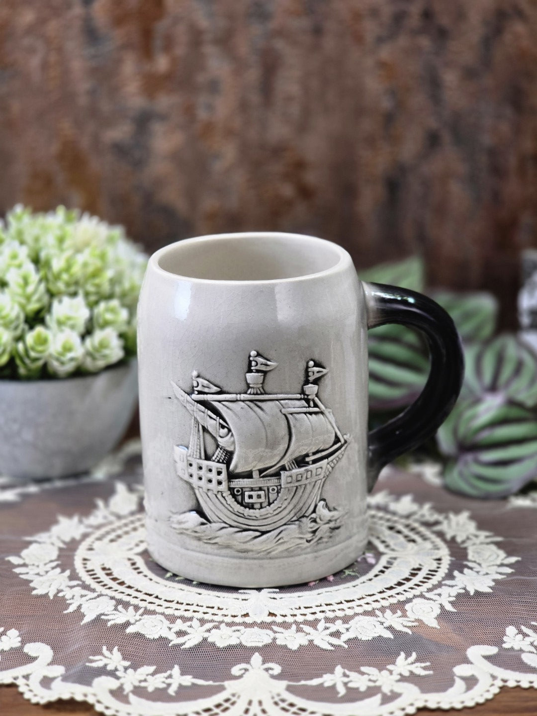 Vintage Sitzendorf Bierkrug aus grauem Porzellan mit plastischem Segelschiff-Relief und dunkel glasiertem Henkel in Frontalansicht
