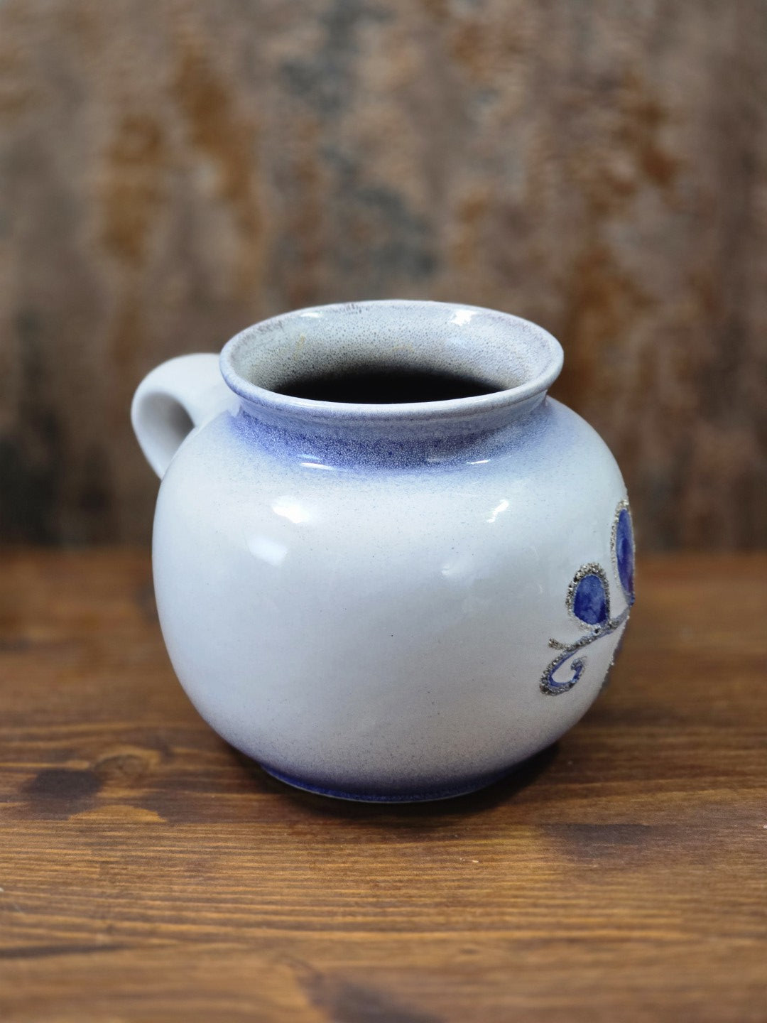 Vintage Strehla Keramikvase mit kleinem Henkel, heller Glasur und seitlich auslaufendem blauem Blumendekor auf Holztisch