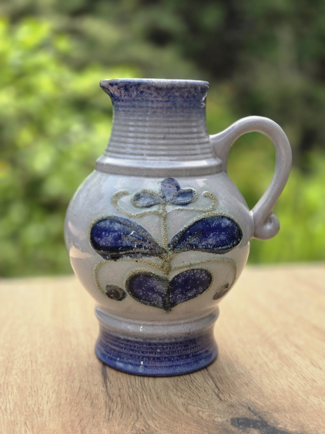 Graublauer Vintage Keramikkrug von Strehla mit kobaltblauem Fuß, Henkel und floralem Dekor in Blau und Violett.