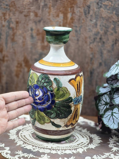 Keramikvase mit blau-grünem Blumendekor, braunen Streifen und Hand als Größenvergleich auf Spitzendecke