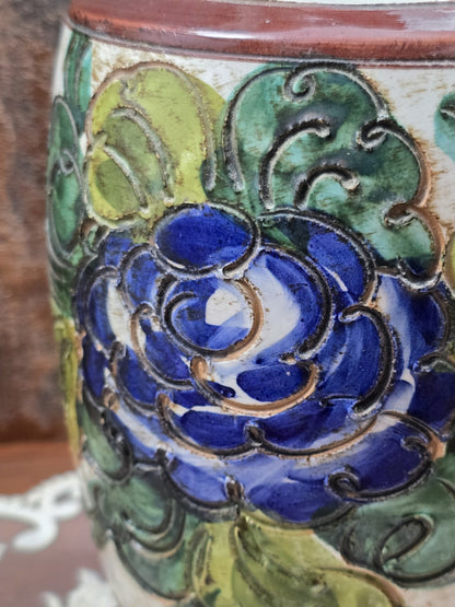 Keramikvase mit blauem Blütenrelief, grünen Blättern und glänzender Glasur in Detailaufnahme