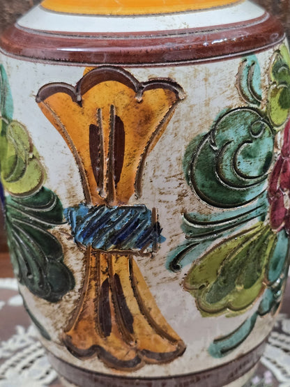 Keramikvase mit gelbem Reliefmotiv, grünen Ornamenten und braunem Zierband in seitlicher Nahaufnahme