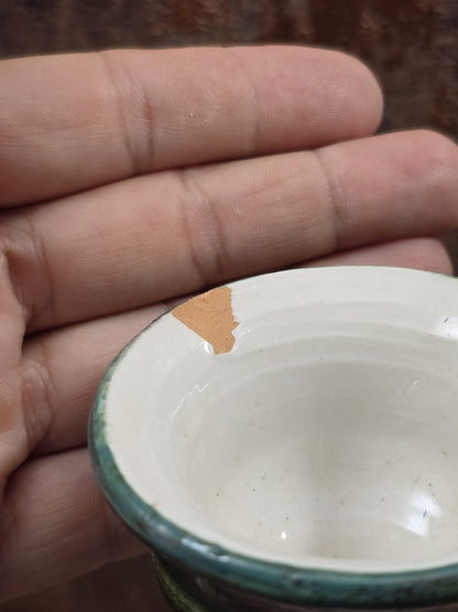 Keramikvase mit grünem Rand, sichtbarem Chip an der Öffnung und Hand als Größenvergleich