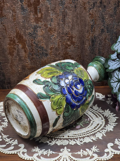 Keramikvase liegend mit blauem Blumendekor, grünen Blättern und sichtbarer Bodenansicht auf Spitzendecke