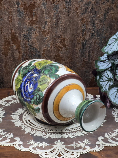 Keramikvase liegend mit Halsöffnung, gelbem Ring, braunem Zierband und blauem Blumendekor auf Spitzendecke
