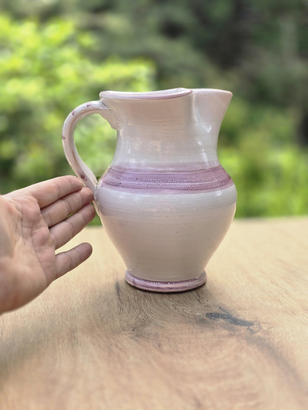 Vintage Keramikkrug zur Größenansicht mit Hand, cremeweiß glasiert mit violettem Band und bauchiger Form.