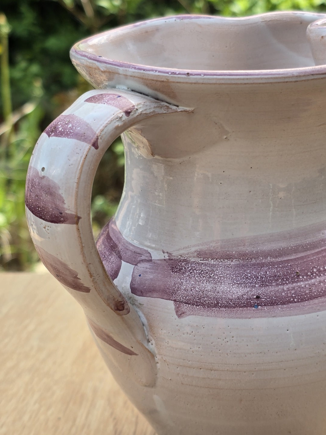 Nahaufnahme von Henkel, Rand und violettem Dekorband des handgemachten Vintage Keramikkrugs.