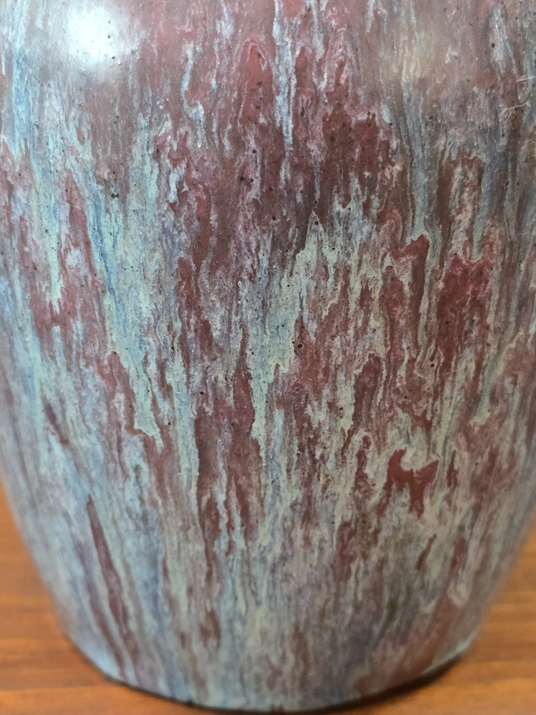 Vintage Keramikvase mit unregelmäßig verlaufender Glasur in Rosé, Hellblau und Grün in einer Detailaufnahme der Oberfläche.