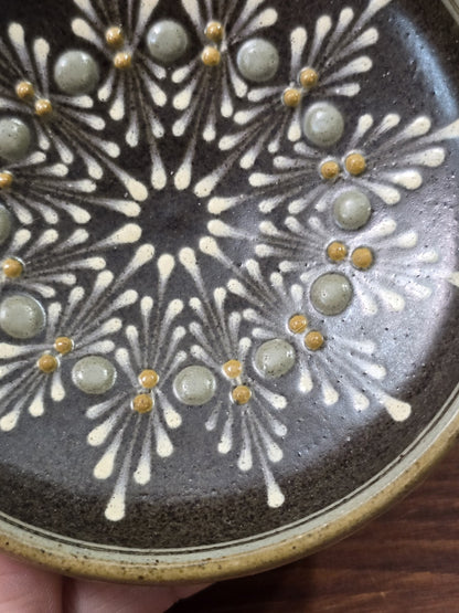 Vintage Keramikteller mit radialem Dekor aus weißen Linien, grauen Rundelementen und gelben Reliefpunkten in Nahaufnahme