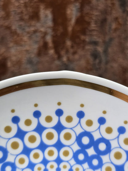 Vintage Porzellanuntertasse mit blauem und goldenem Kreisdekor, weißem Spiegel und Goldrand in Hand gehalten