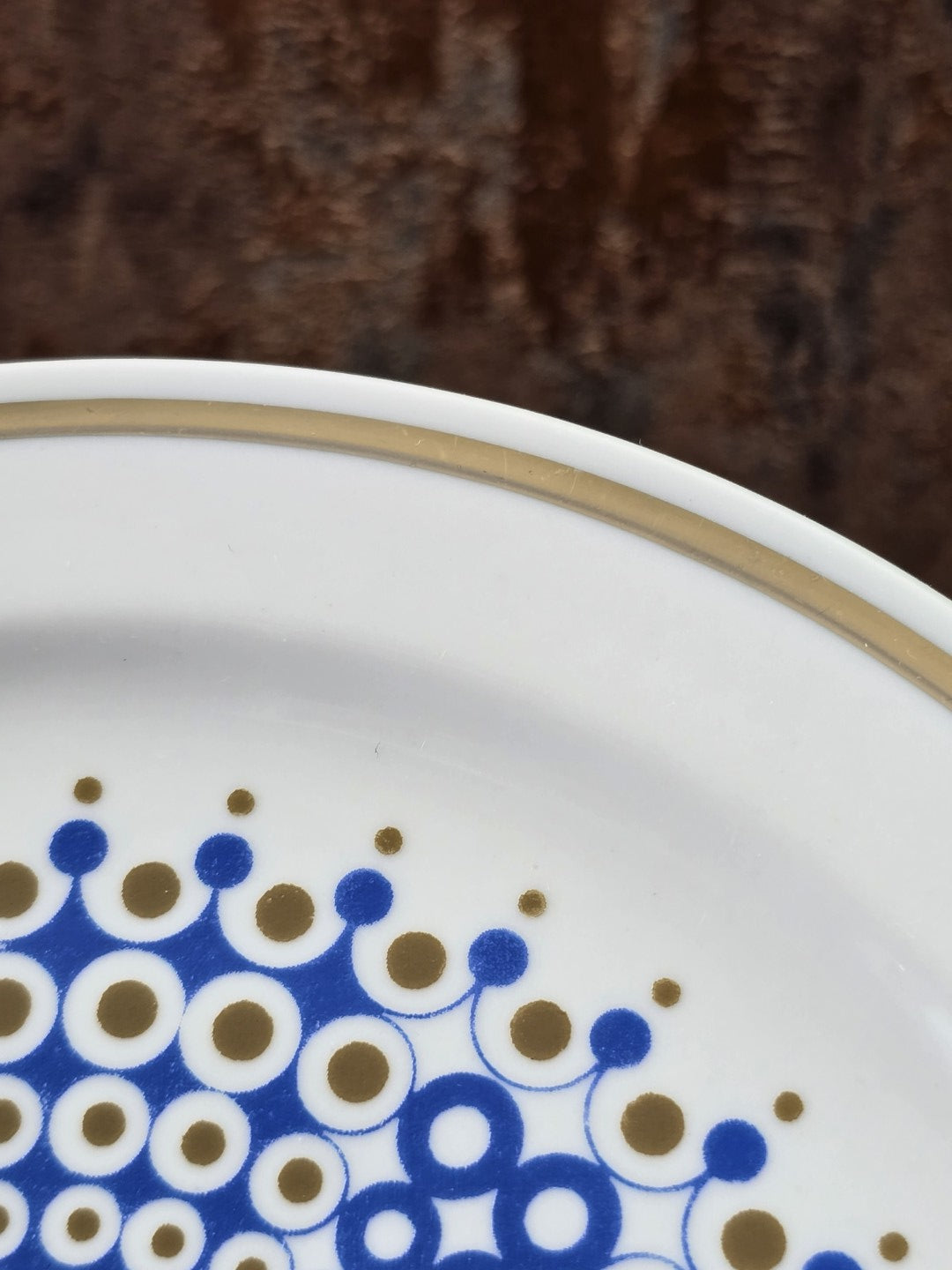 Vintage Porzellanteller mit Goldrand und blau-goldenem Punktdekor am Rand in sehr naher Detailansicht
