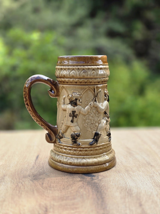 Braun-beiges Westerwald Bierseidel mit Landsknecht Relief, Tatzenkreuz, geschwungenem Henkel und kleiner Chipstelle am Standring.