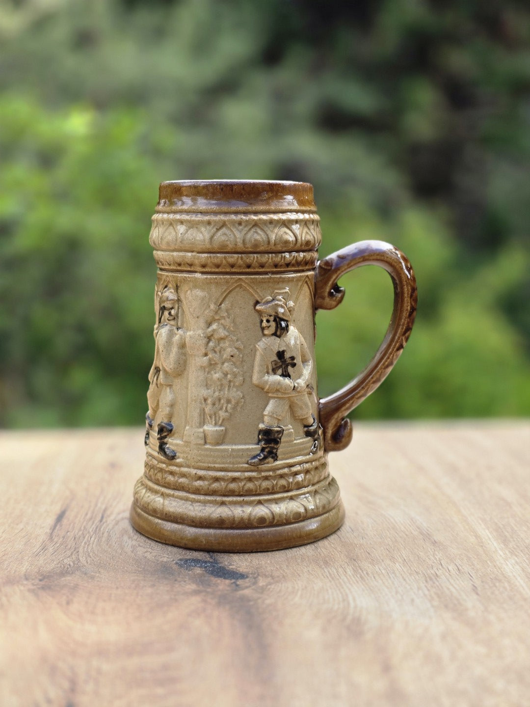 Braun-beiger Bierkrug aus dem Westerwald mit Landsknecht Reliefdekor, Tatzenkreuz Detail, gebogenem Henkel und kleiner Standring-Chipstelle.
